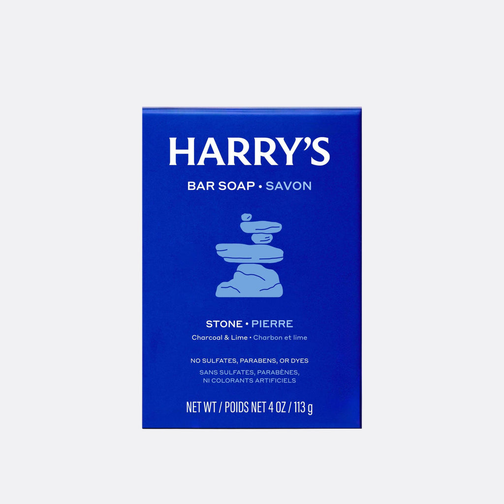 A blue rectangular box of Harry's Bar Soap in the Stone / Pierre scent, featuring white text and a light blue stacked stone graphic, centered on a light gray background.