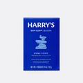 A blue rectangular box of Harry's Bar Soap in the Stone / Pierre scent, featuring white text and a light blue stacked stone graphic, centered on a light gray background.