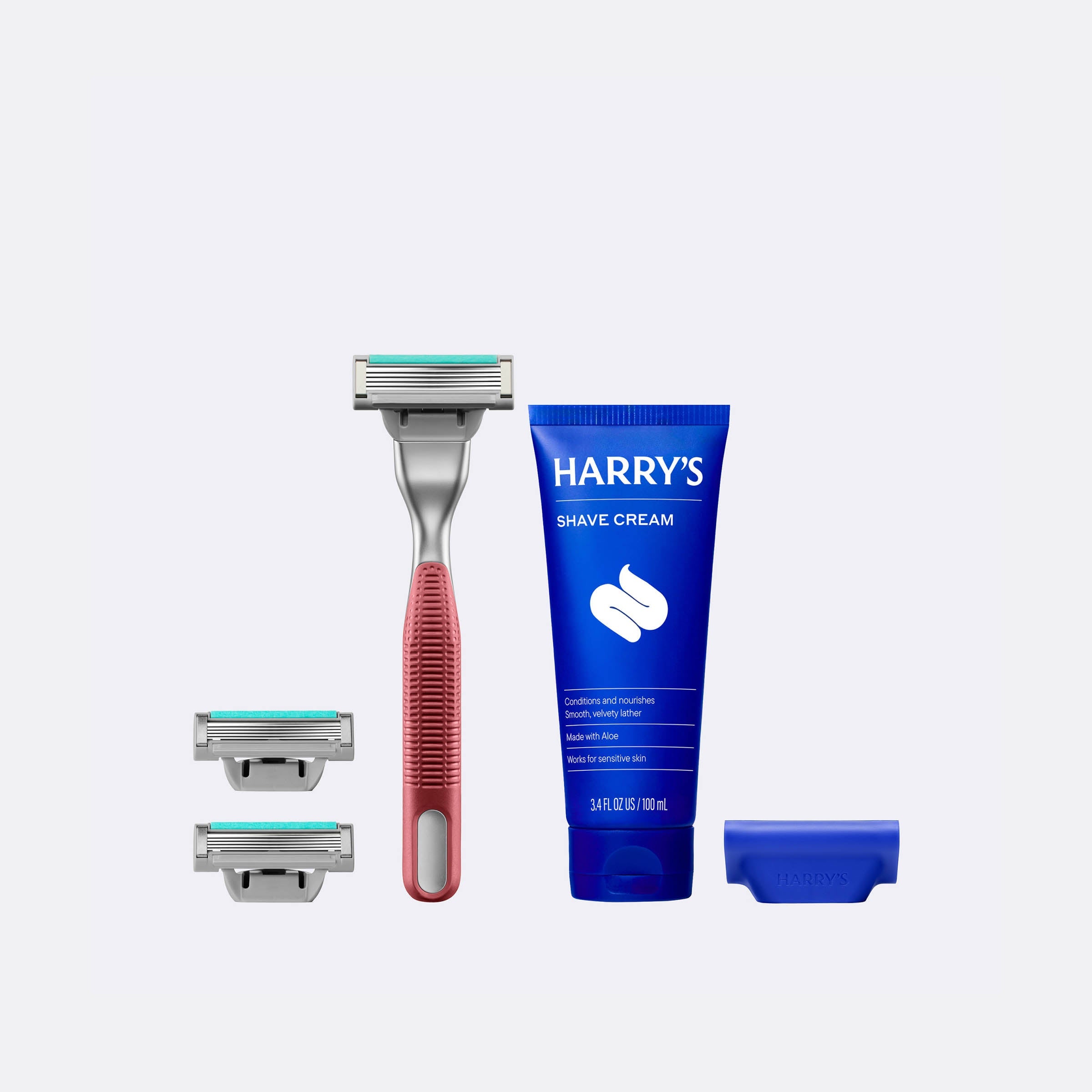 Harry's shaving kit with a razor, razor heads, and shave cream on a white background