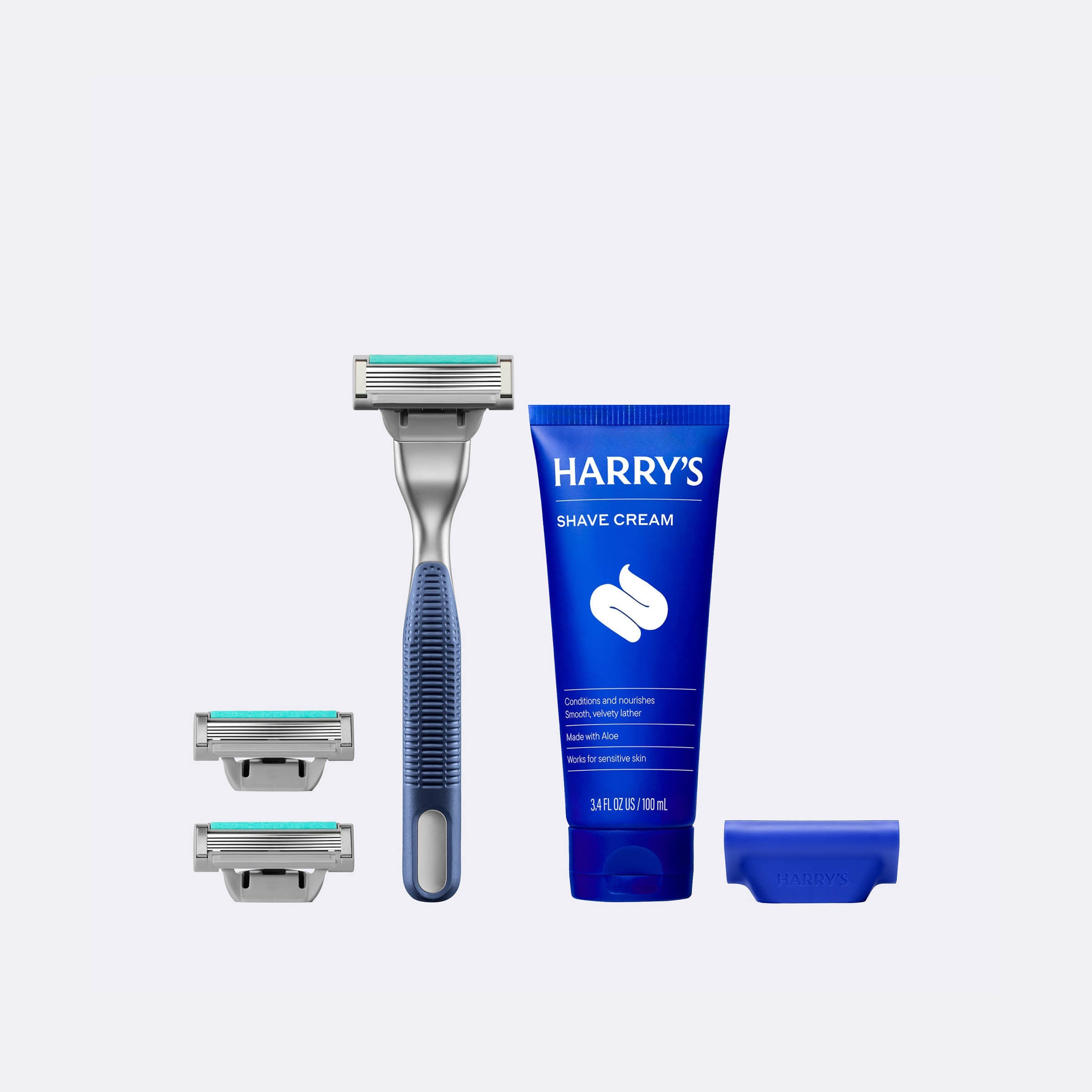 Harry's shaving kit with a razor, three razor heads, and a tube of shave cream on a white background