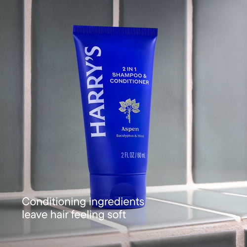 Blue tube of Harry's 2-in-1 shampoo & conditioner on a reflective surface with a neutral background