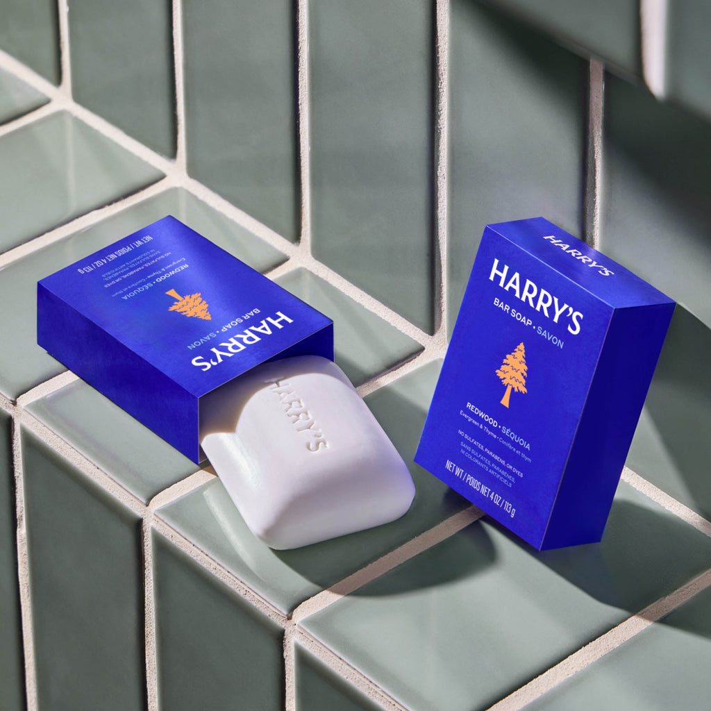 Two blue boxes of Harry's Cedar Soap Savon with white soap bars, arranged on a glossy green tiled surface.