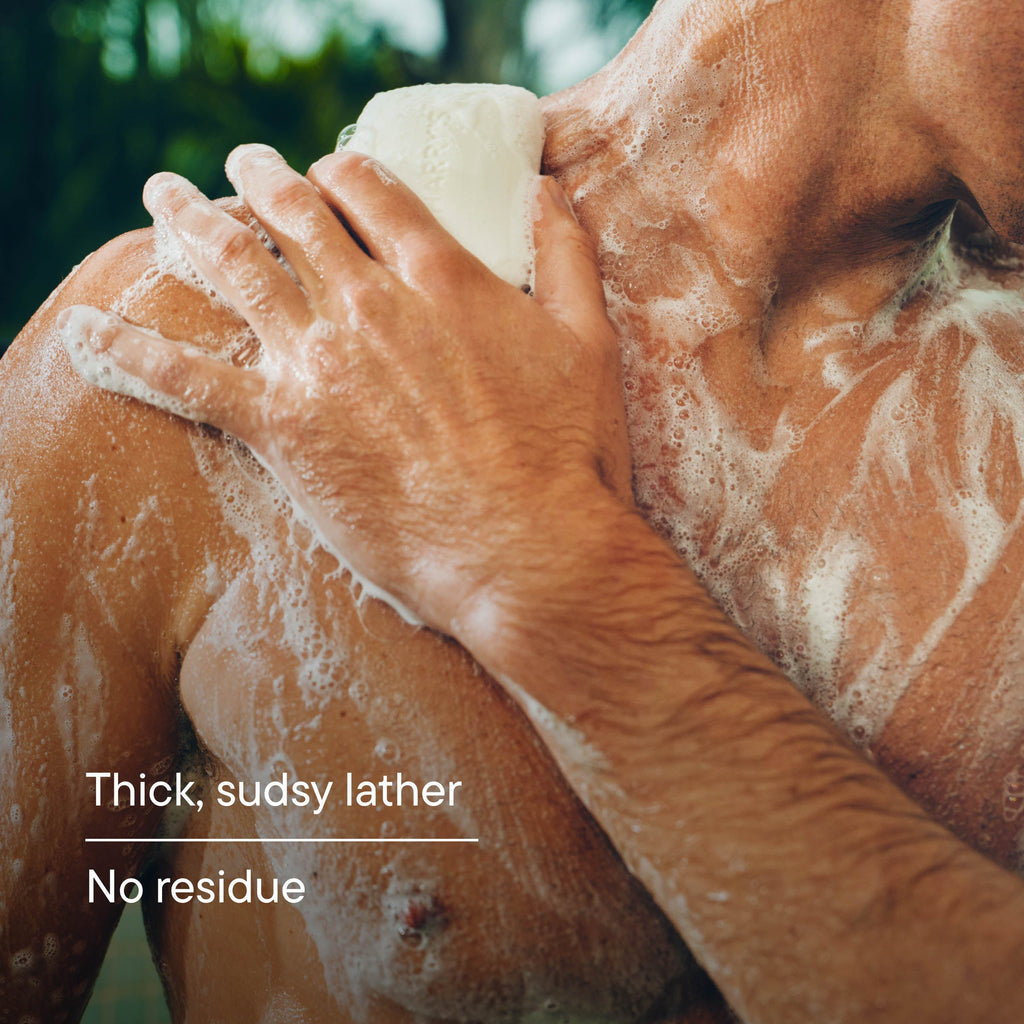 Person scrubbing their back with soap, showing thick suds and no residue.