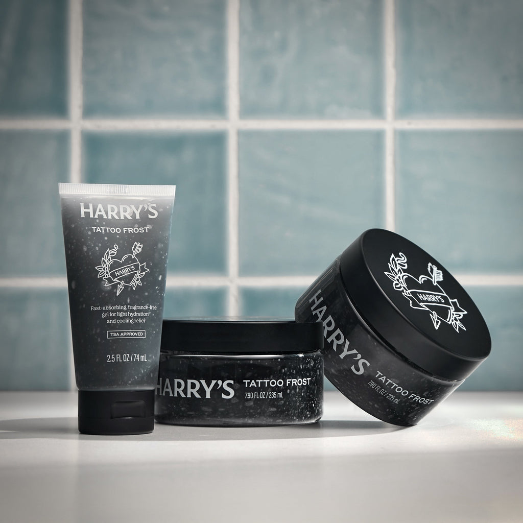 Three containers of 'Harry's Tattoo Frost' on a tiled bathroom counter.