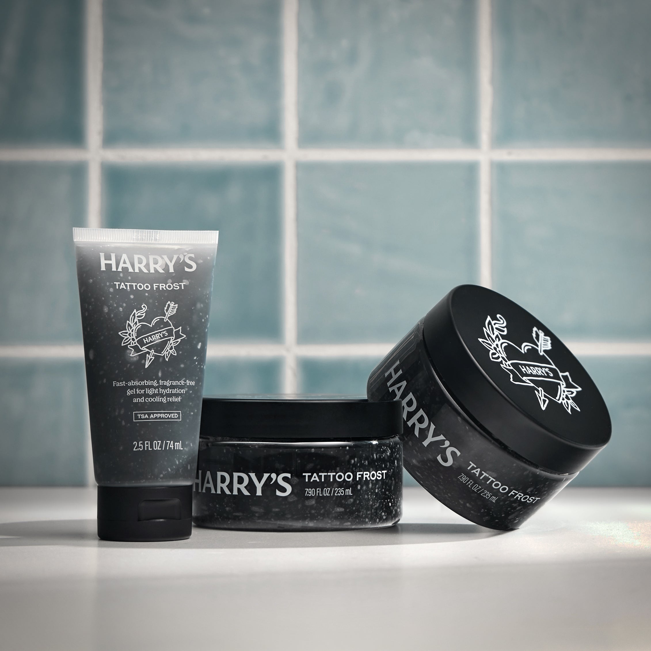 Three containers of 'Harry's Tattoo Frost' on a tiled bathroom counter.