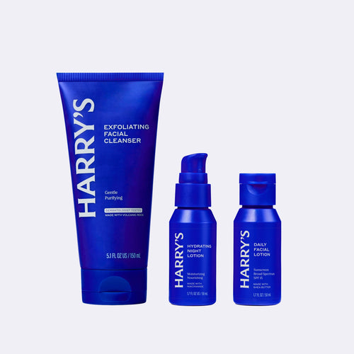 Three blue bottles of Harry's skincare products on a white background