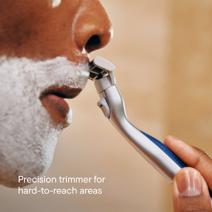 Person using a precision trimmer on their beard with a blurred background
