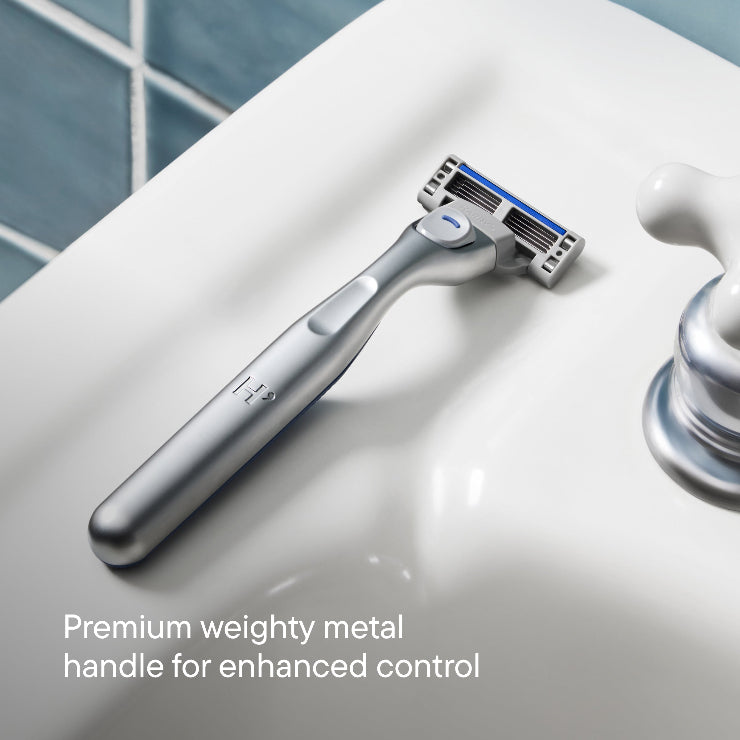 Shaving razor on a bathroom counter with text about premium metal handle