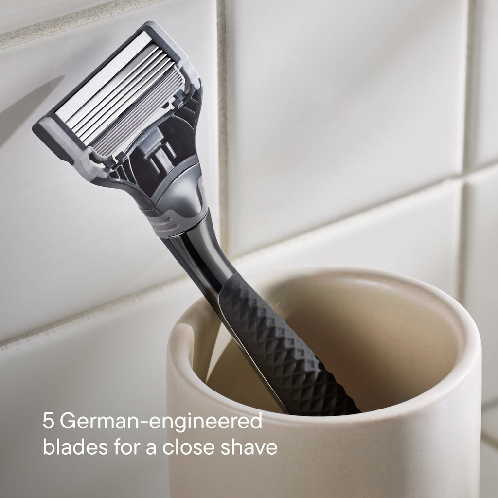 Shaving razor in a white cup with tiled wall background